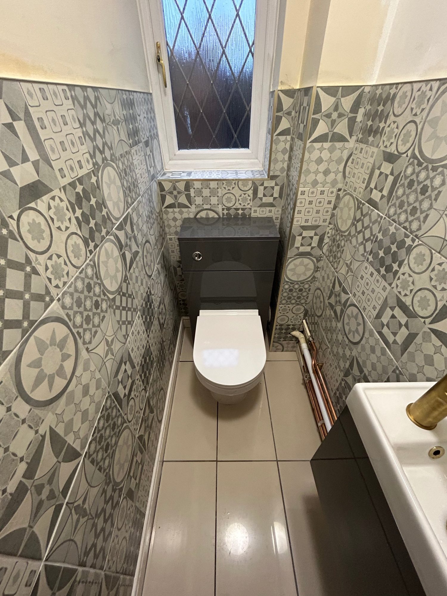 Cloakroom with patterned wall tiles and wall-hung toilet