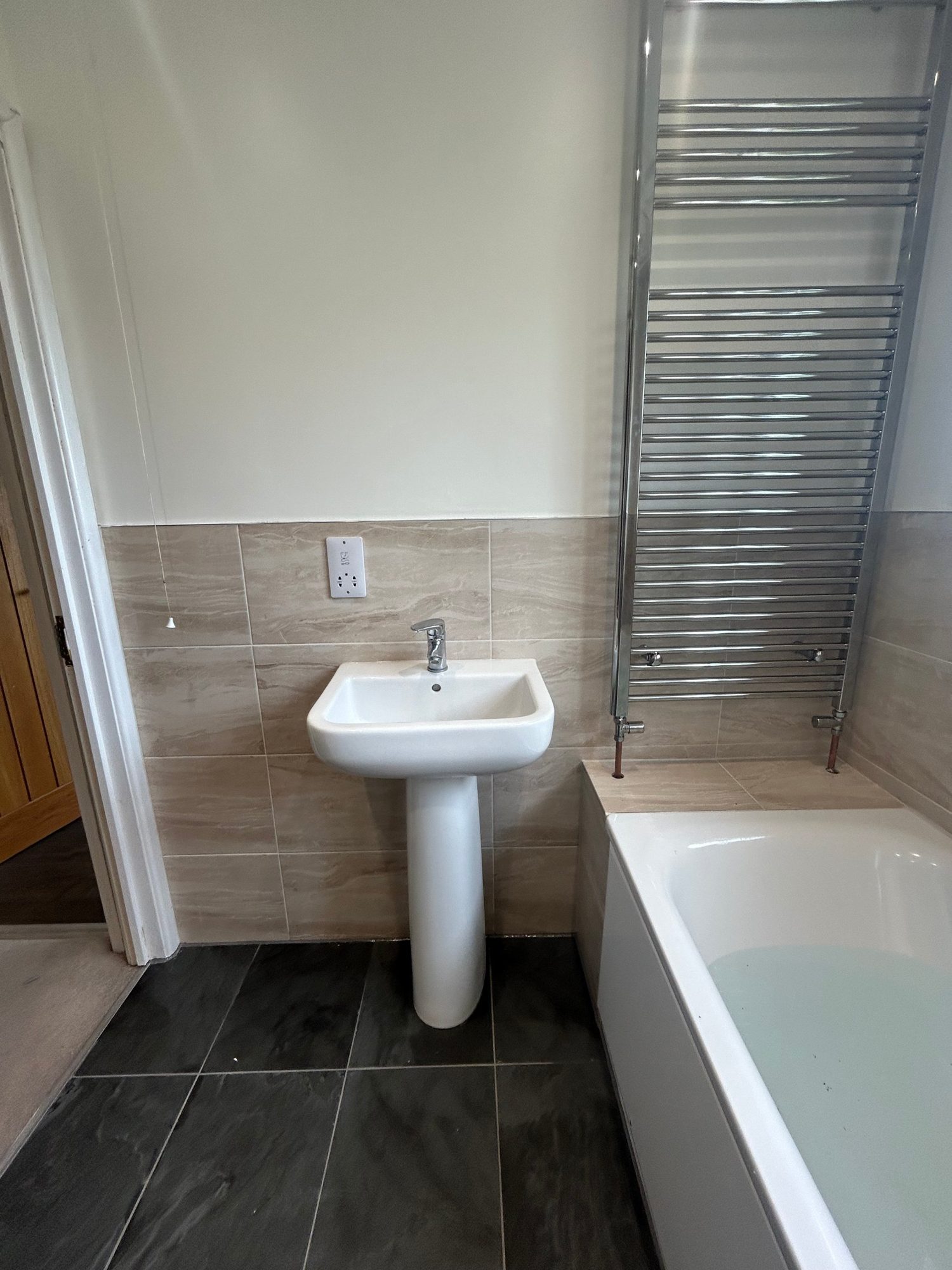 Bathroom with pedestal basin, bath and chrome towel radiator