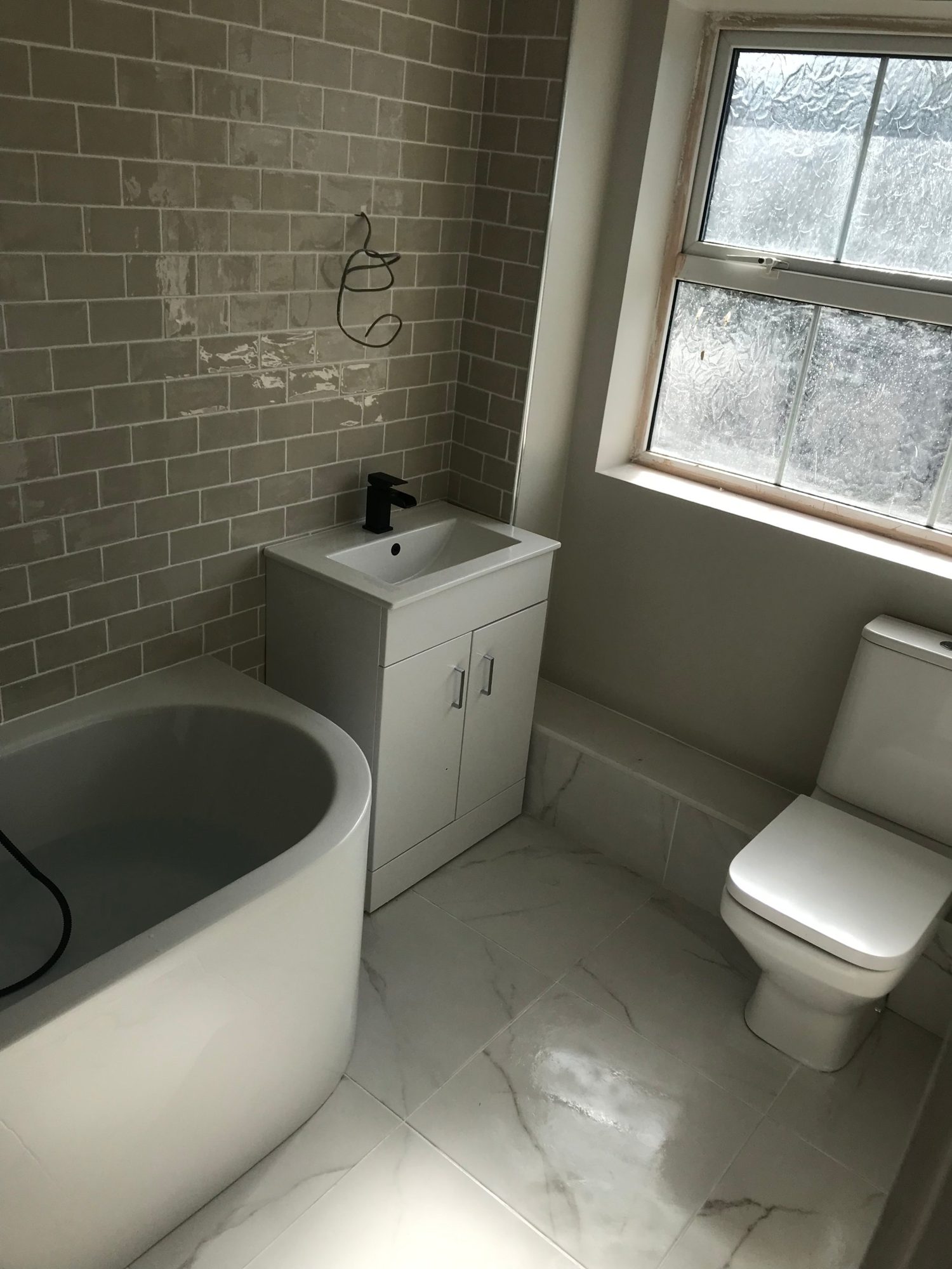 Bathroom with white vanity, bath and grey metro tiles