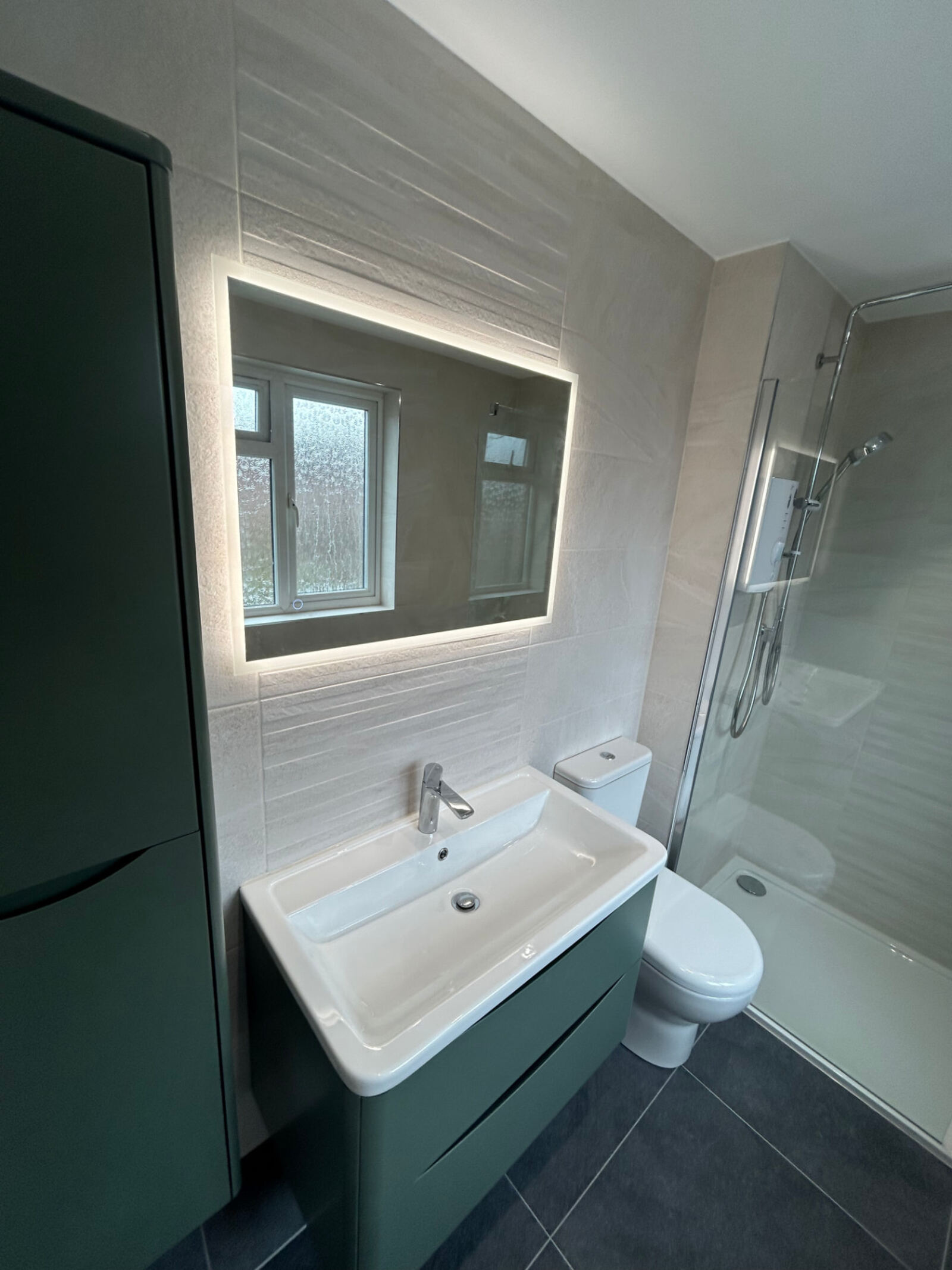 After: refitted shower room with LED mirror, textured tiles and dark floor