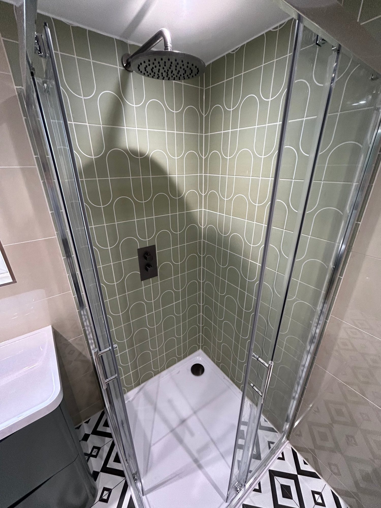 Shower enclosure with patterned green tiles and rainfall shower
