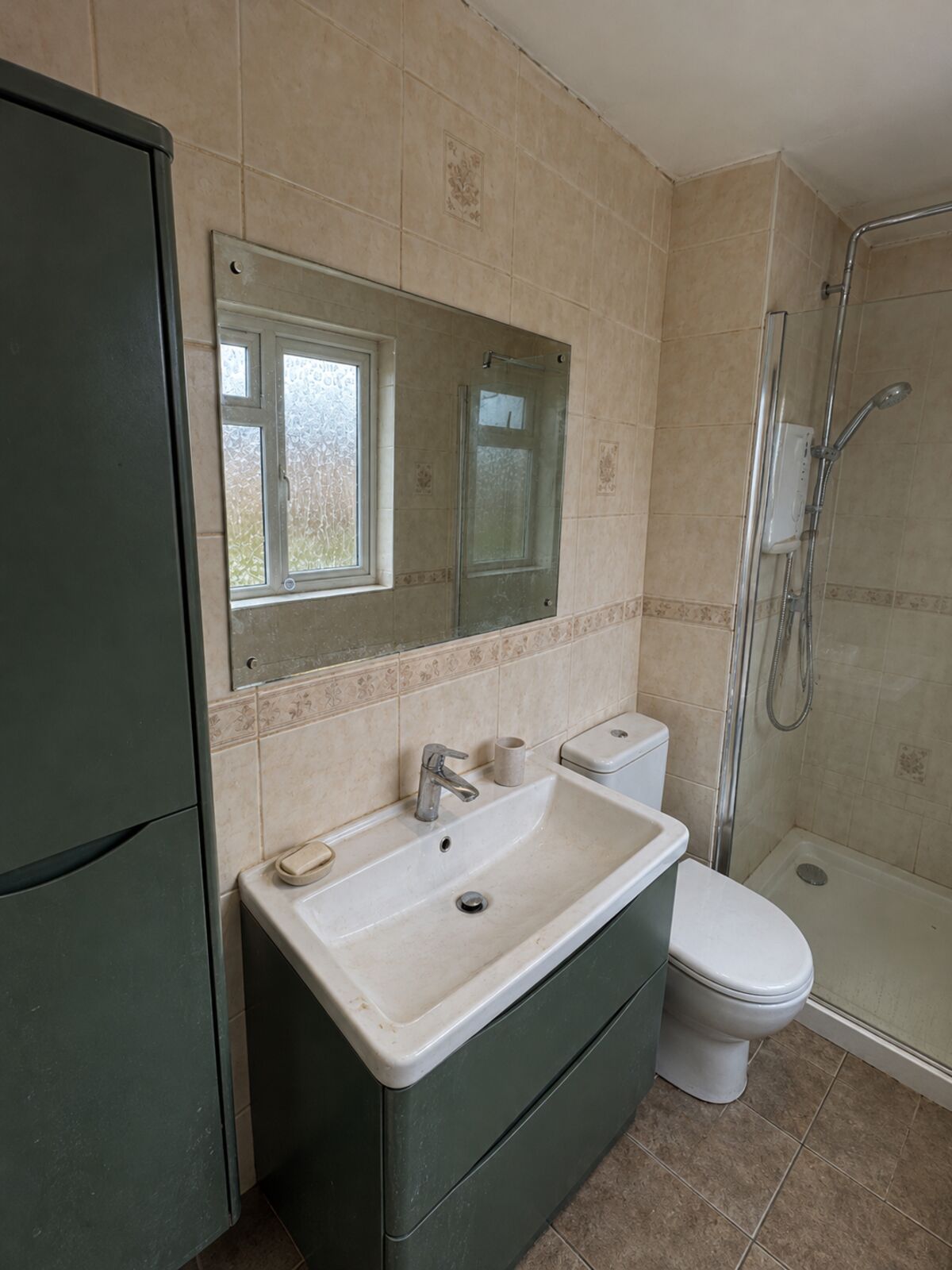 Before: dated beige tiles, plain mirror and worn floor