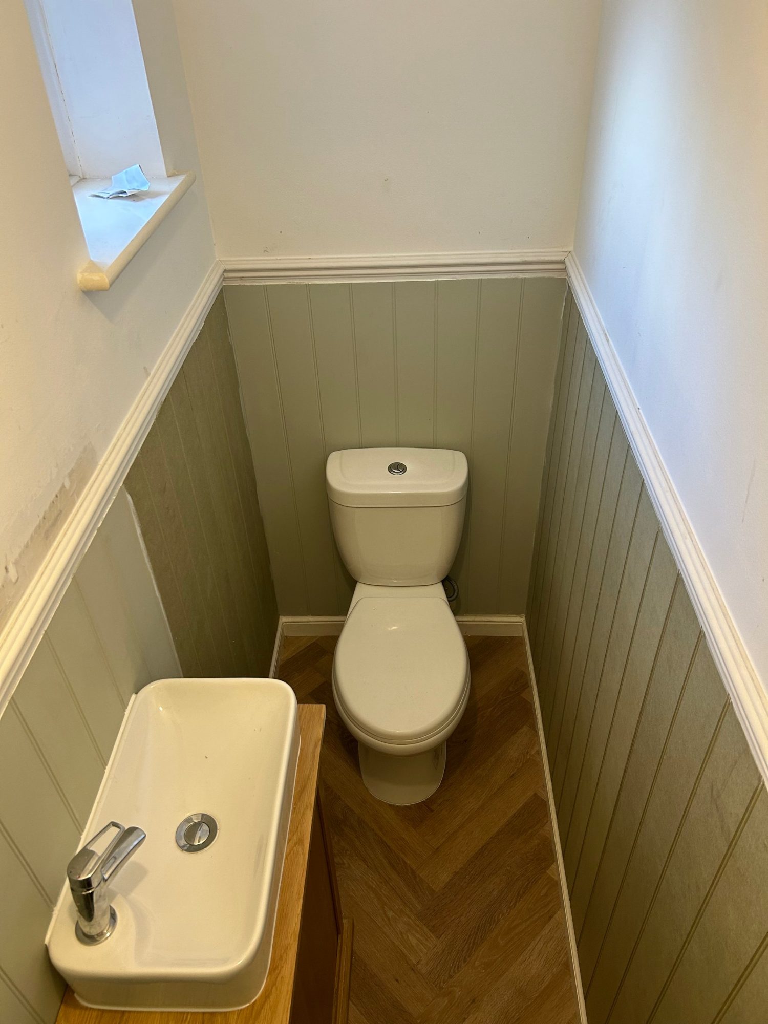 Downstairs cloakroom with panelled walls and herringbone floor
