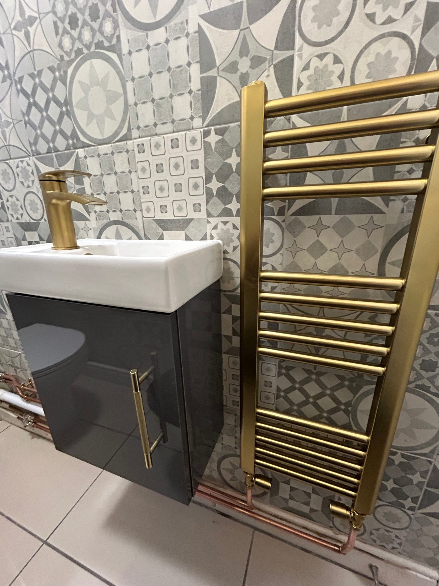 Cloakroom installation with patterned tiles and gold tap by Camms Bathrooms
